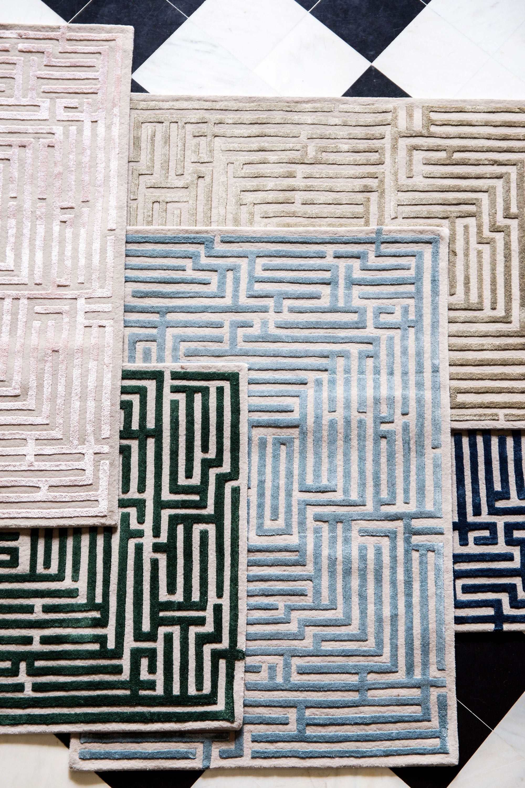 A stack of Anatolia Hand-Tufted Maze luxury floor rugs in a variety of colors