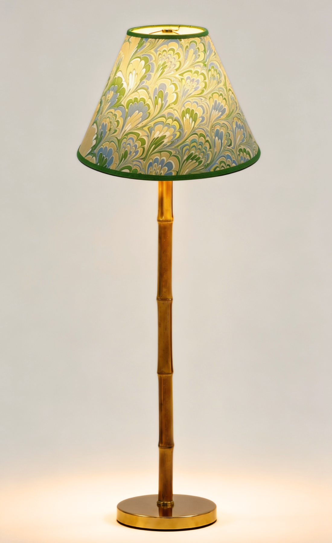 Caslon green marbled lamp shade lit on a brass faux bamboo lamp base.