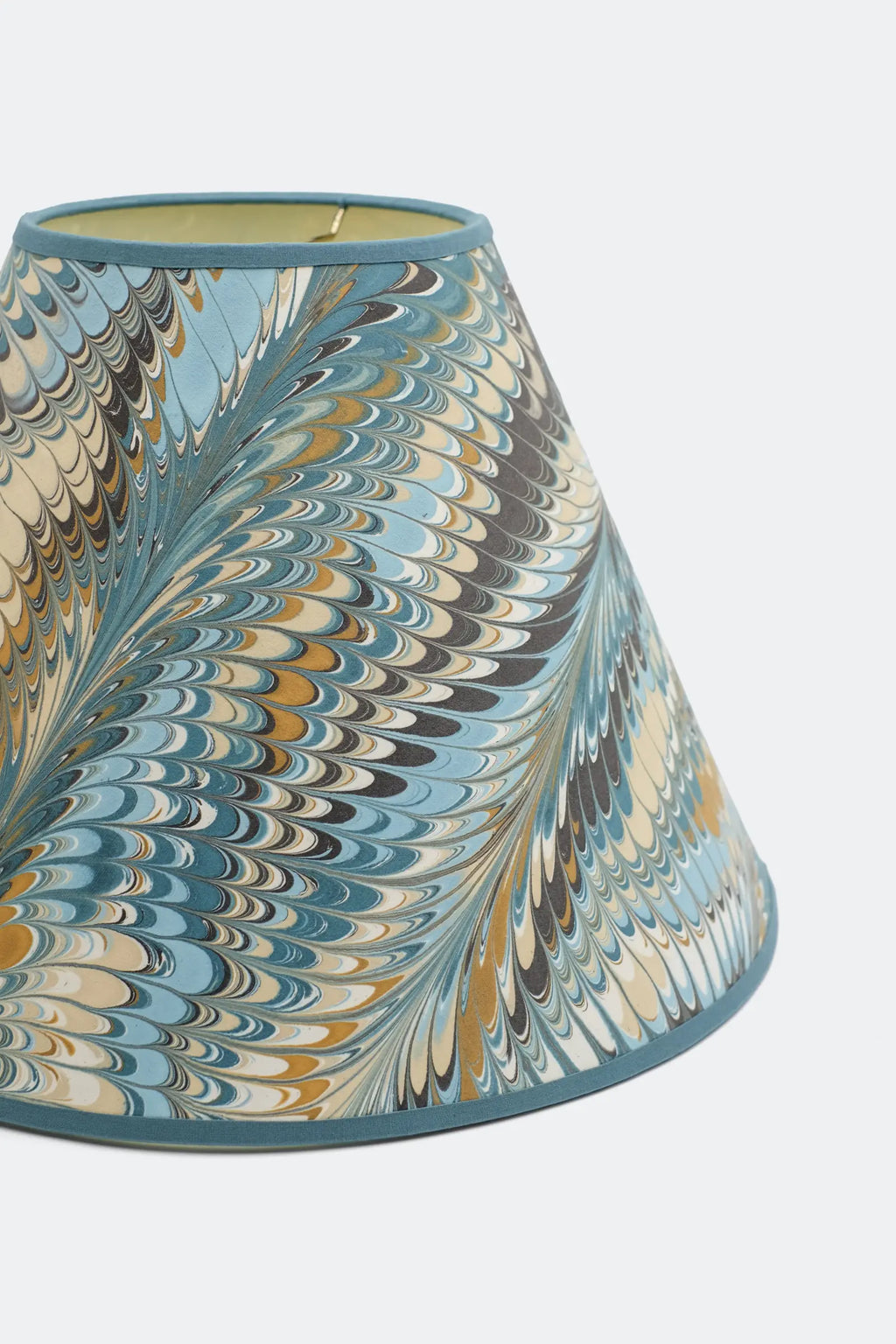 Close view of the Kelmscott marbled lamp shade showing the combed feather pattern in blue, ochre and cream.