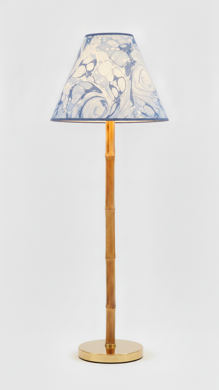 Chiswick blue and white marbled lamp shade lit on a brass faux bamboo lamp base.