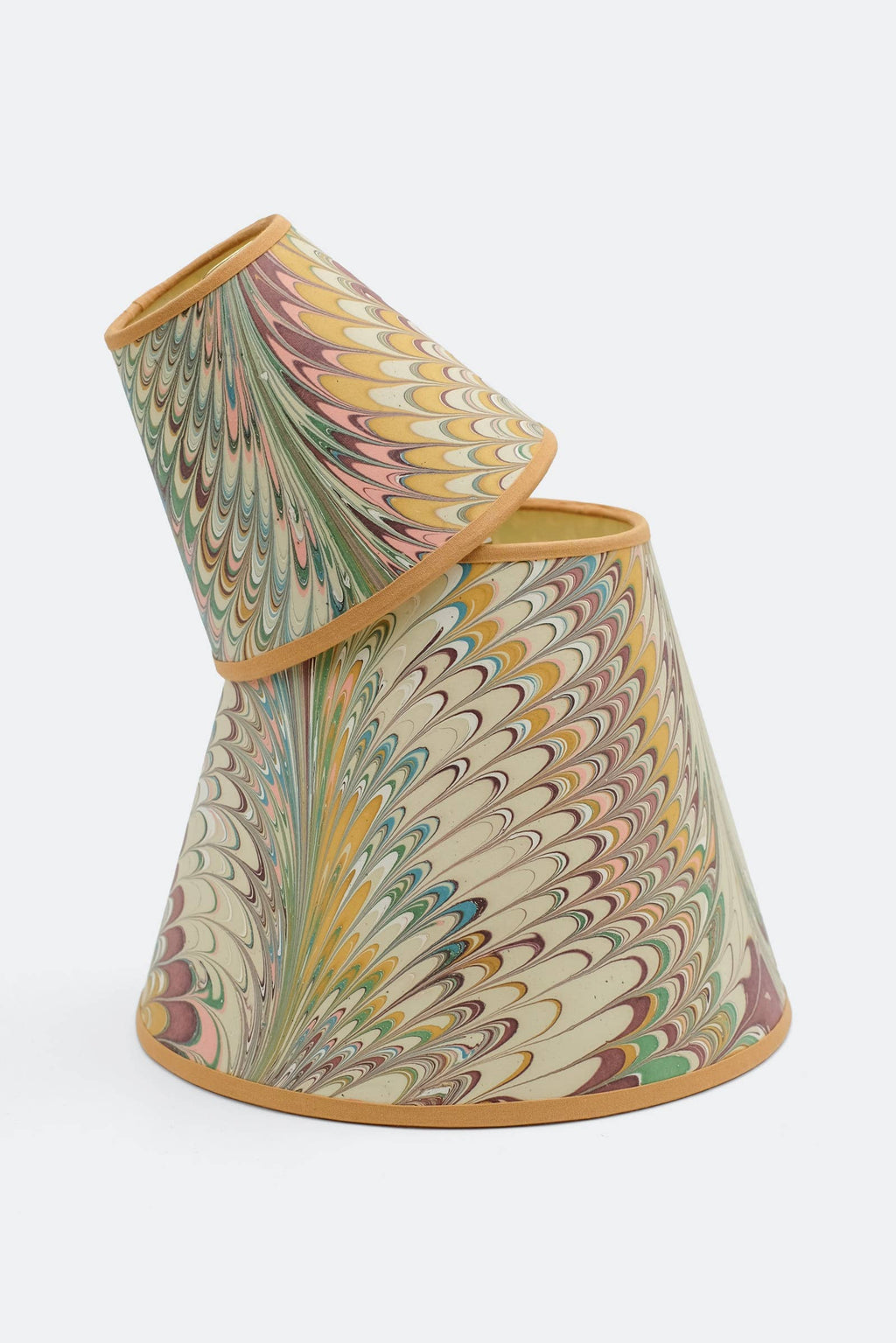 Two Doves hand-marbled lamp shades stacked, showing how the blush and gold feather marbling varies from shade to shade.