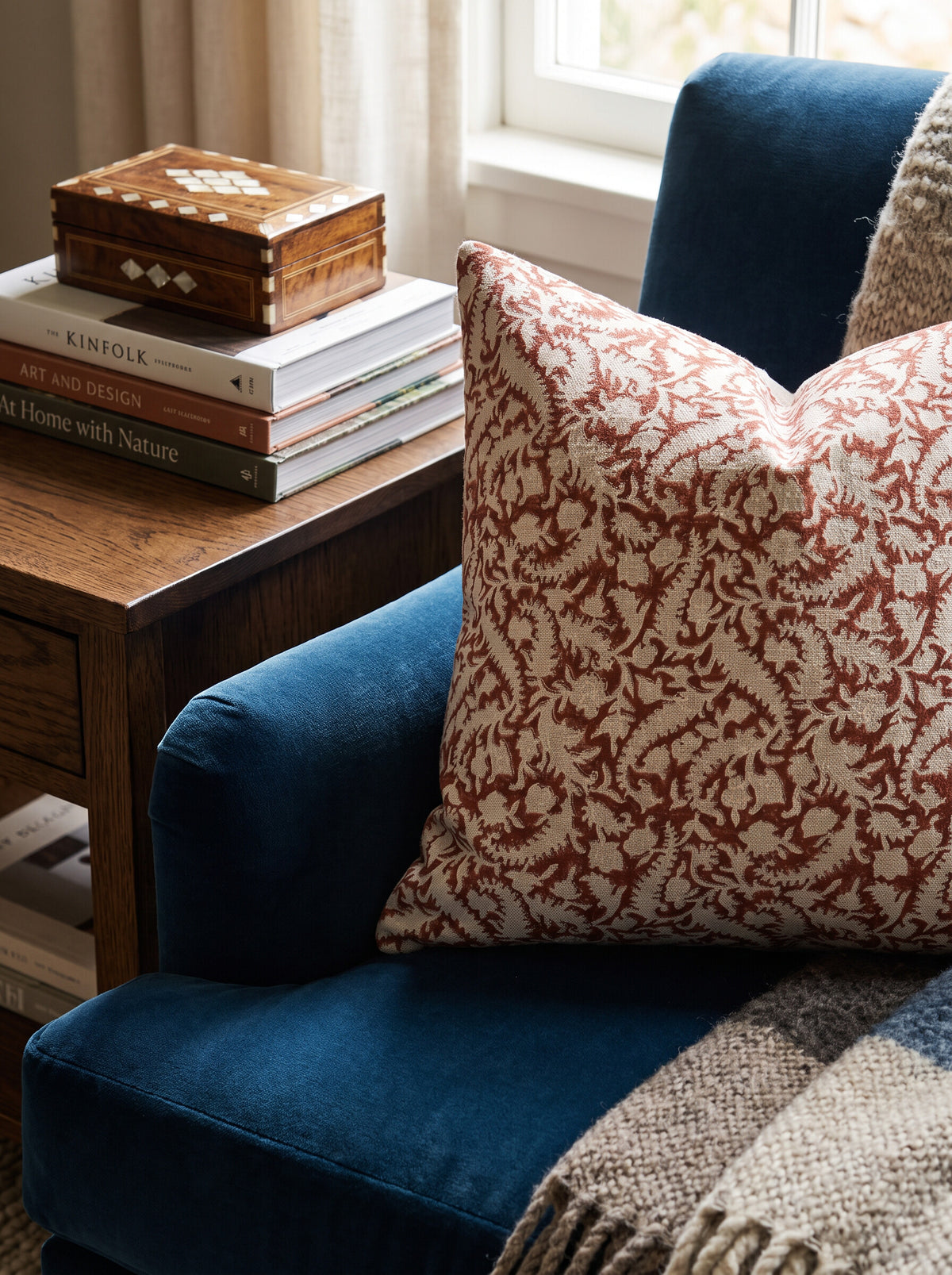 The Blackland block print pillow cover in maroon and cream styled on a navy velvet sofa