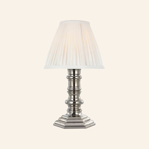 12-inch Ellis cordless candlestick lamp in polished silver with a turned column base, stepped octagonal foot and white pleated silk shade, by Kevin Francis Design