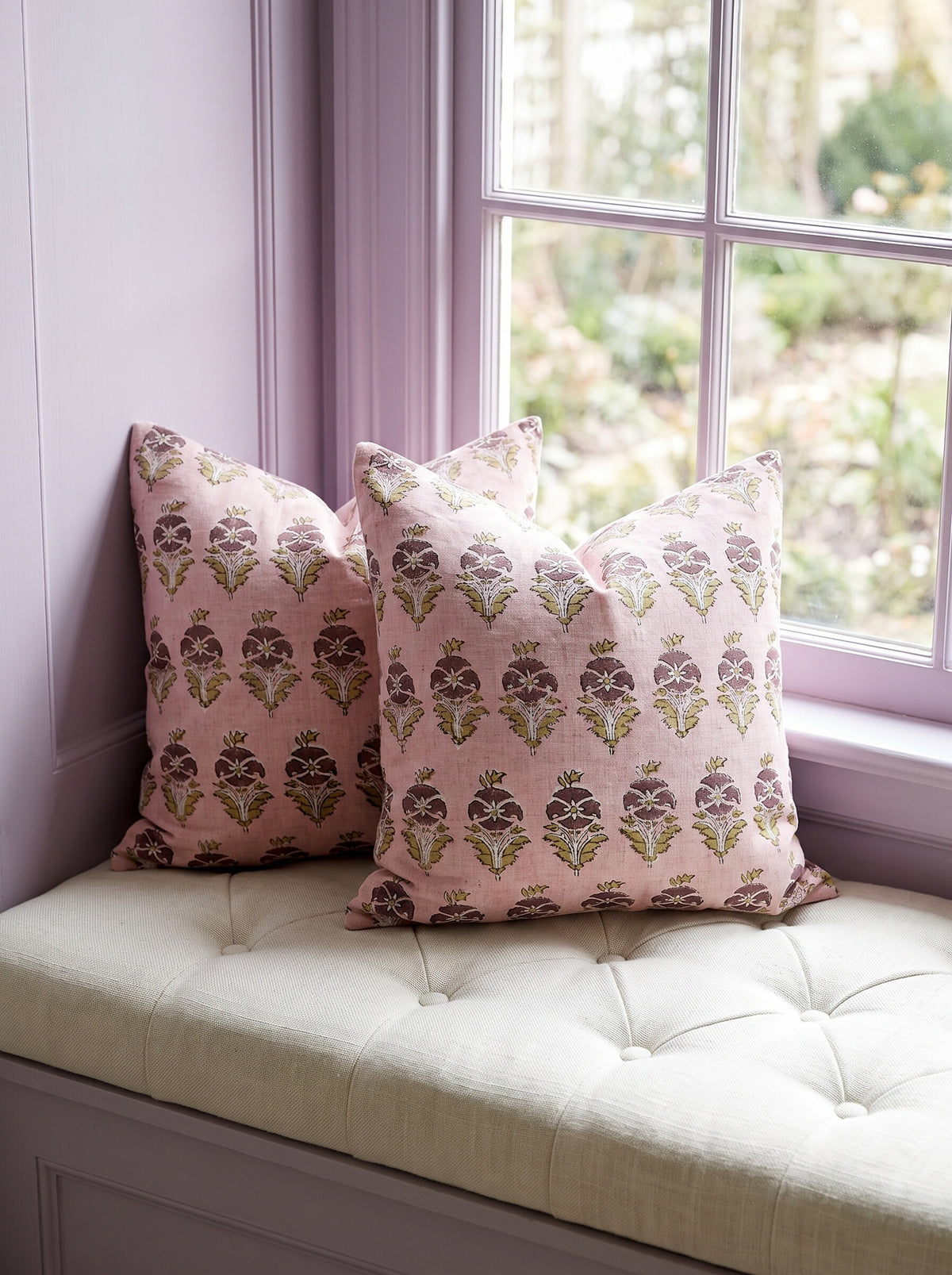 Two Kingsboro block print pillow covers in pink and plum styled on a tufted window seat