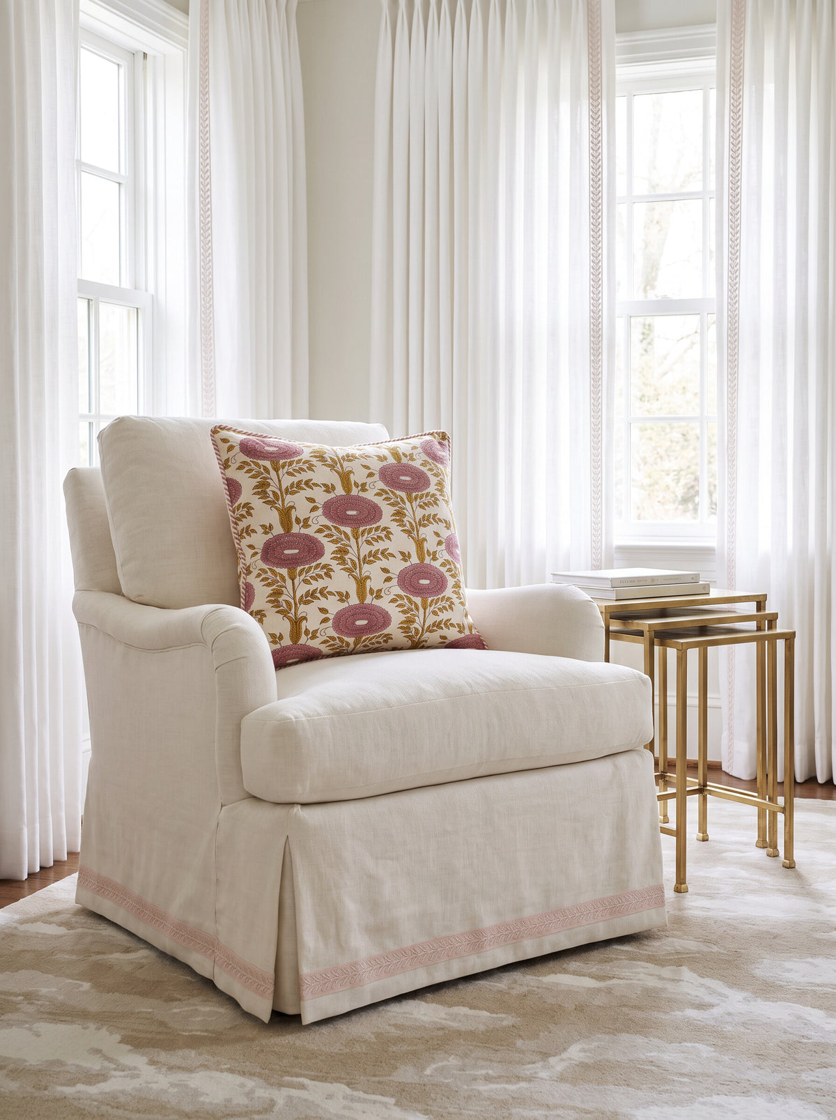 The Knollwood block print pillow cover in pink and mustard styled on a cream skirted armchair