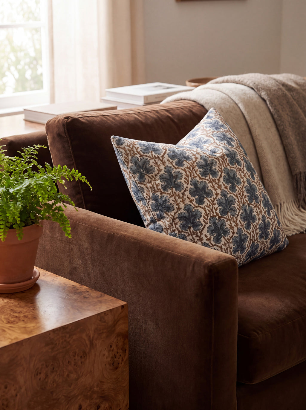 The Longleaf block print pillow cover in navy and brown styled on a brown velvet sofa